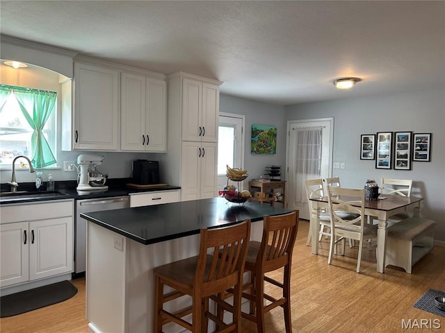 404 Crystal Ln, Rosebud, MO 63091 - kitchen featuring a sink, dishwasher, dark countertops, a breakfast bar, and light wood-type flooring