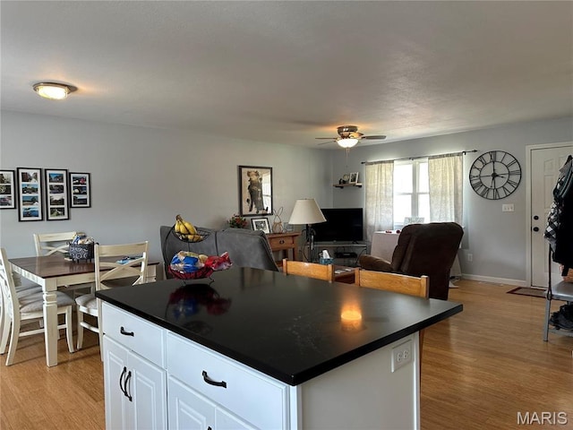 404 Crystal Ln, Rosebud, MO 63091 - kitchen with dark countertops, a ceiling fan, light wood-type flooring, and a kitchen island