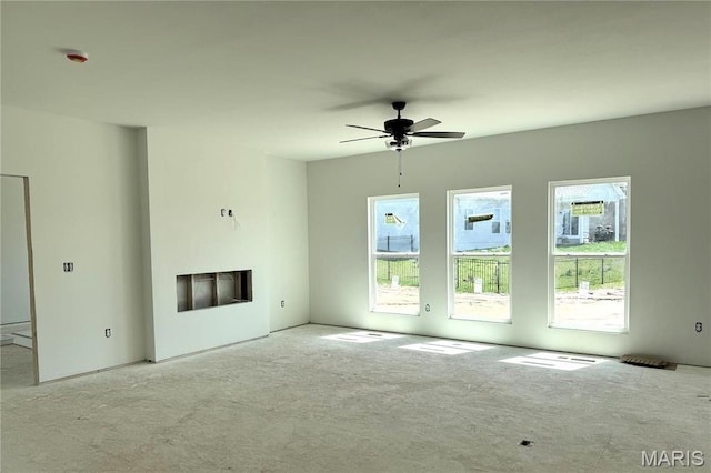unfurnished living room featuring healthy amount of natural light, a ceiling fan, carpet floors, and a fireplace