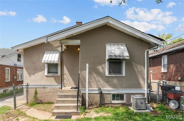 2326 Patton Ave, Saint Louis, MO 63144 - rear view of property featuring stucco siding, fence, a gate, central AC unit, and a chimney