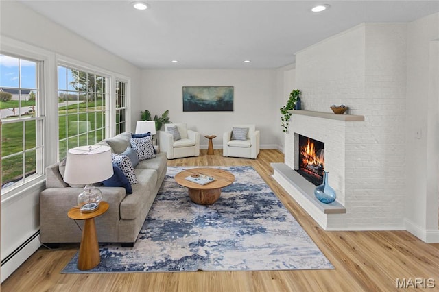 living area featuring a baseboard heating unit, a brick fireplace, wood finished floors, baseboards, and recessed lighting