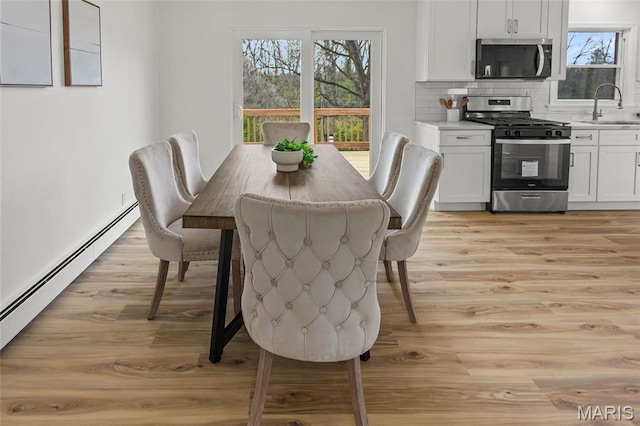 dining room featuring light wood finished floors, plenty of natural light, and a baseboard radiator