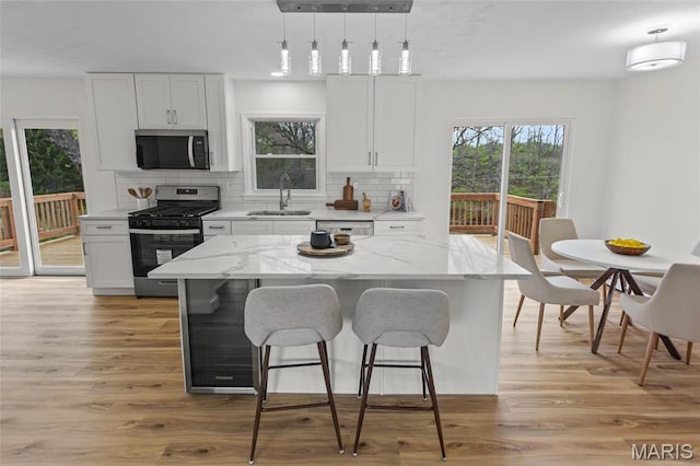 kitchen with appliances with stainless steel finishes, a sink, healthy amount of natural light, and decorative backsplash