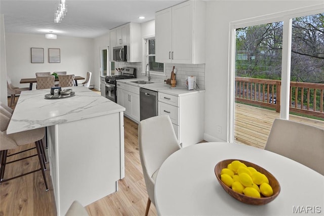 kitchen with stainless steel appliances, a sink, a center island, decorative backsplash, and a breakfast bar