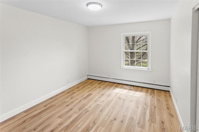 spare room featuring baseboard heating, wood finished floors, and baseboards