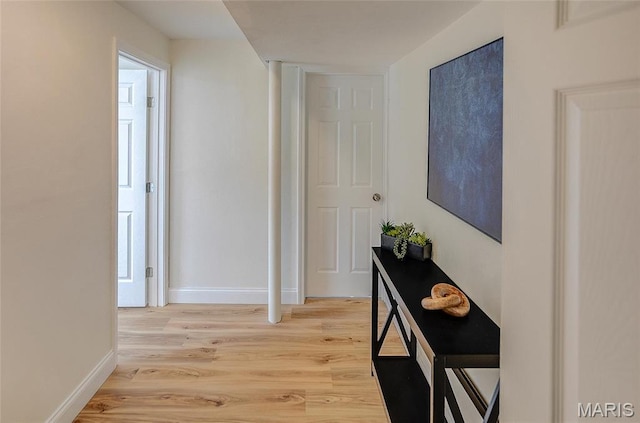 hall with light wood-style floors and baseboards