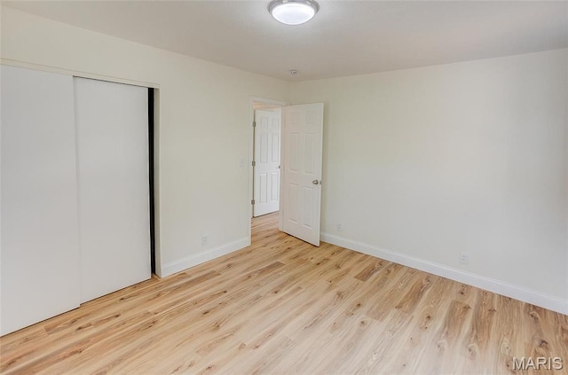 unfurnished bedroom with wood finished floors, baseboards, and a closet