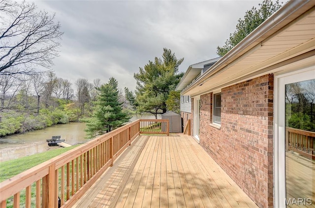 deck with a storage unit, an outbuilding, and a water view