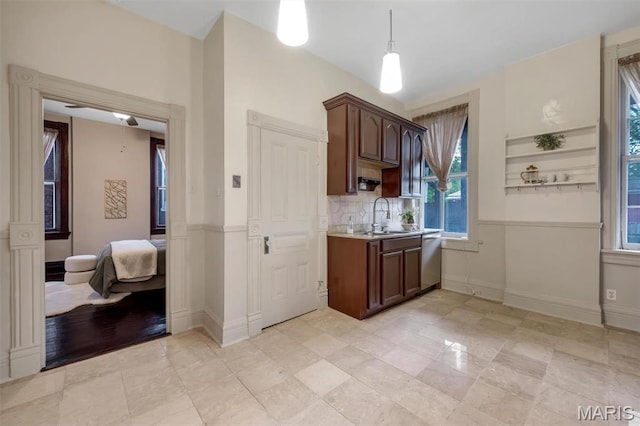 2811 Pennsylvania Ave, Saint Louis, MO 63118 - kitchen with stainless steel dishwasher, light countertops, a sink, baseboards, and decorative backsplash