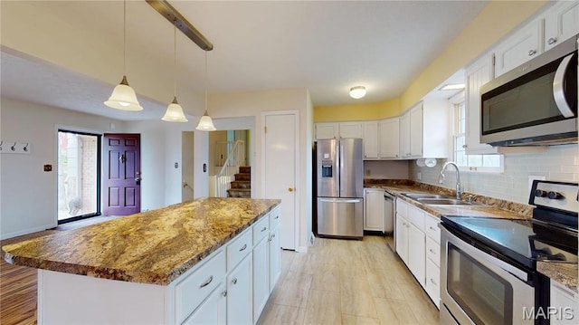 1402 Liberty Dr, Rolla, MO 65401 - kitchen featuring appliances with stainless steel finishes, a sink, white cabinetry, a kitchen island, and pendant lighting