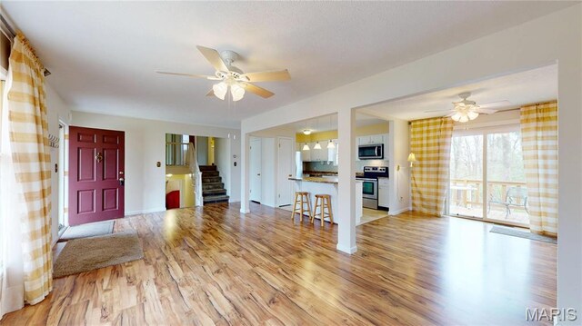 1402 Liberty Dr, Rolla, MO 65401 - unfurnished living room featuring ceiling fan, light wood-style flooring, stairway, and baseboards