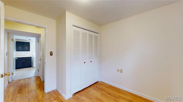 1402 Liberty Dr, Rolla, MO 65401 - unfurnished bedroom featuring light wood-style floors, a closet, baseboards, and a textured ceiling