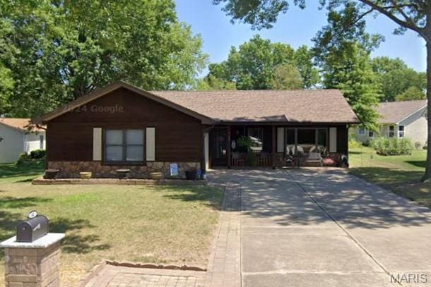 ranch-style house with concrete driveway, a front yard, covered porch, and stone siding