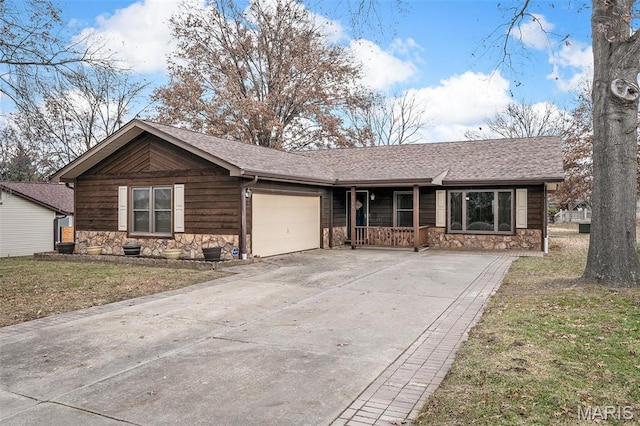 view of front of house with stone siding, a garage, covered porch, driveway, and a front lawn