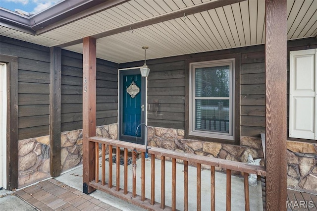 doorway to property with stone siding and covered porch