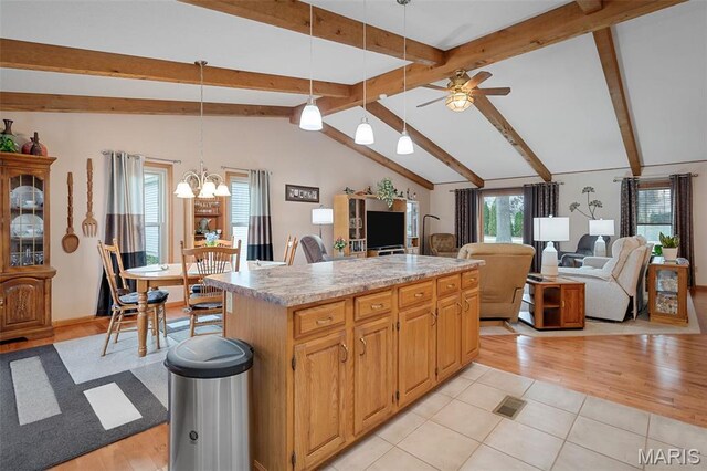kitchen with ceiling fan, open floor plan, a chandelier, a kitchen island, and light countertops
