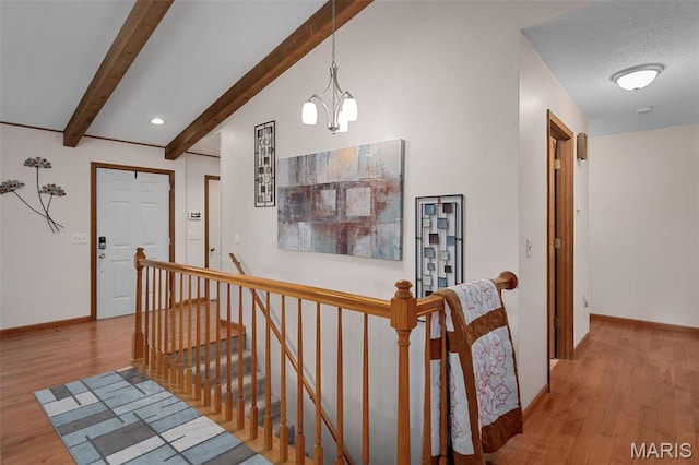 hallway featuring an upstairs landing, beam ceiling, wood finished floors, a chandelier, and baseboards
