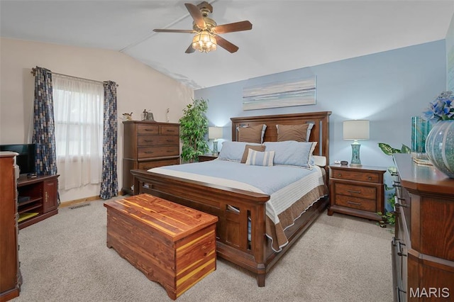 bedroom with vaulted ceiling, light colored carpet, and a ceiling fan