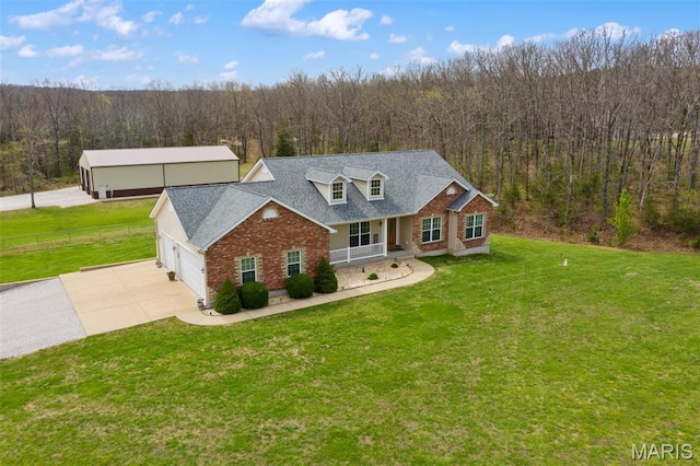 view of front of property with a view of trees, a garage, brick siding, concrete driveway, and covered porch