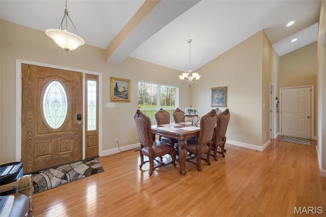 dining area with baseboards, light wood-style flooring, a chandelier, and lofted ceiling