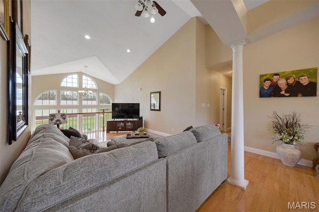 living room with ornate columns, high vaulted ceiling, ceiling fan, baseboards, and light wood-type flooring