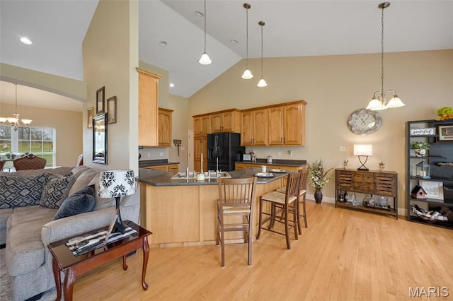 kitchen with a chandelier, black fridge with ice dispenser, open floor plan, dark countertops, and a peninsula