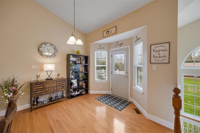 foyer with hardwood / wood-style flooring, baseboards, plenty of natural light, and vaulted ceiling