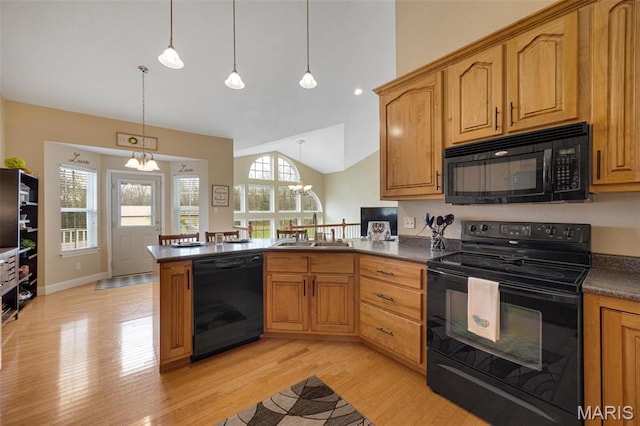 kitchen featuring black appliances, a peninsula, a chandelier, dark countertops, and vaulted ceiling