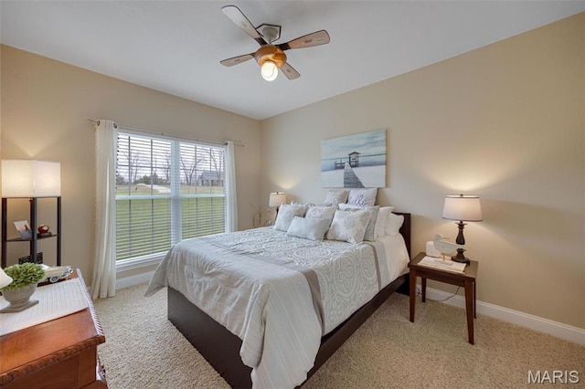 bedroom featuring light colored carpet, baseboards, and a ceiling fan