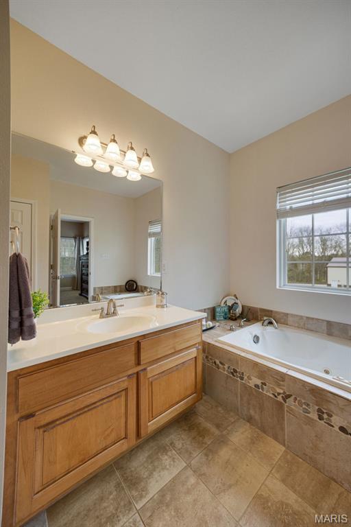 bathroom featuring a garden tub, vanity, and tile patterned floors