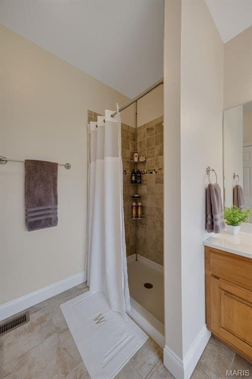 full bathroom with a tile shower, vanity, tile patterned flooring, and baseboards