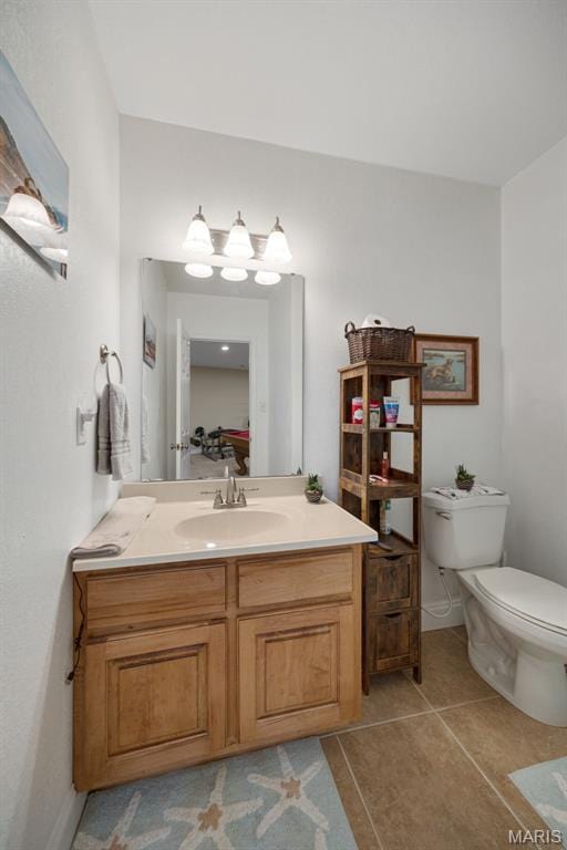 bathroom featuring toilet, vanity, tile patterned flooring, and baseboards