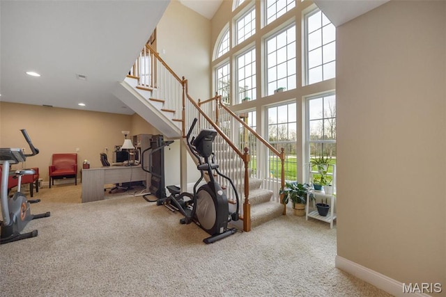 exercise area with carpet, a towering ceiling, baseboards, and recessed lighting