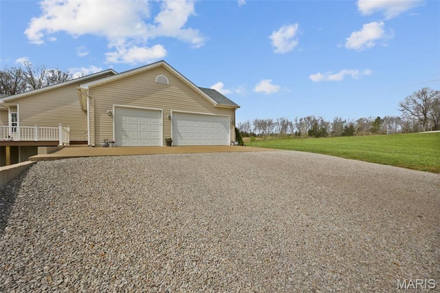 view of side of property with gravel driveway, an attached garage, and a yard
