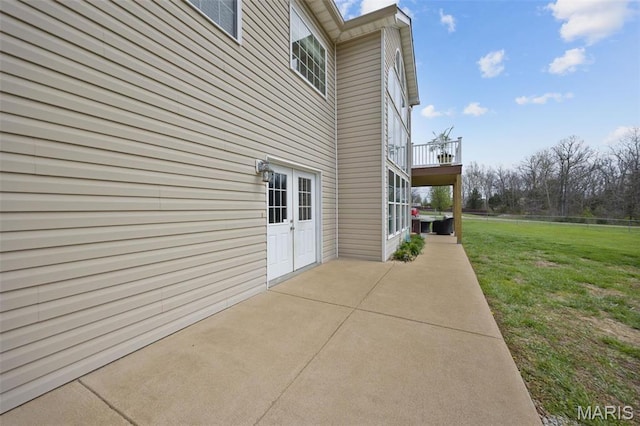 view of side of property featuring a patio area, a yard, and a balcony