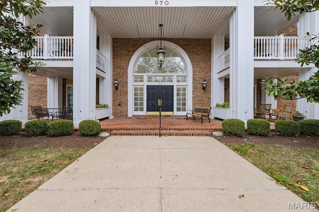 entrance to property featuring a porch and brick siding