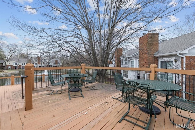 wooden terrace featuring outdoor dining area, a residential view, and a water view