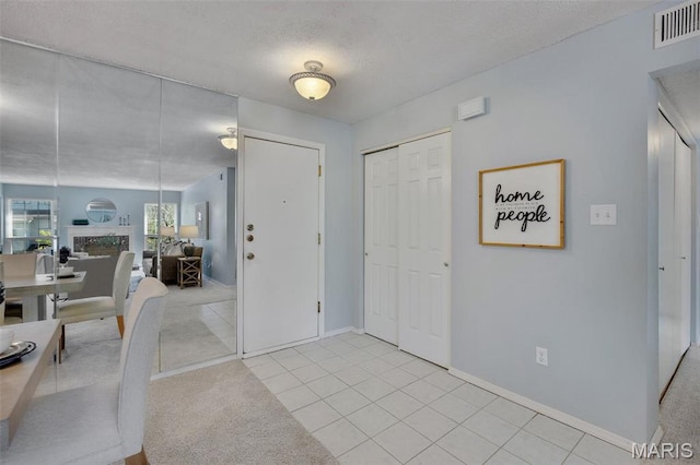 foyer with light tile patterned floors, baseboards, and a textured ceiling