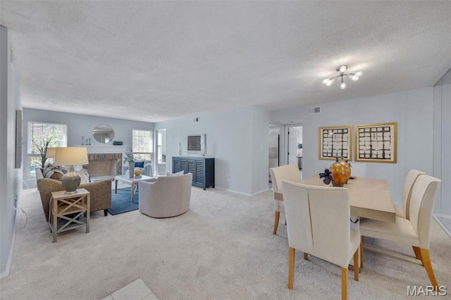 carpeted dining room with a textured ceiling, a brick fireplace, and baseboards