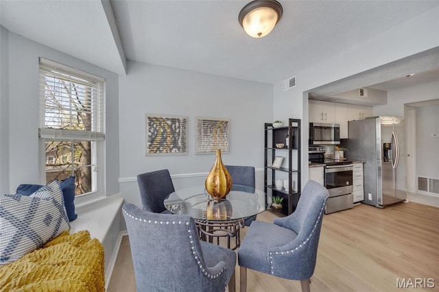 dining area featuring light wood-style floors, baseboards, and a textured ceiling