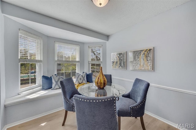 dining space featuring wood finished floors, baseboards, and a textured ceiling