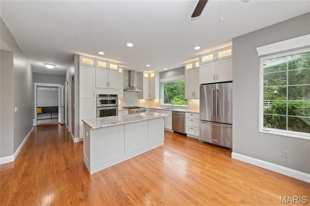 809 Star Ridge Ct, Defiance, MO 63341 - kitchen featuring stainless steel appliances, wall chimney exhaust hood, decorative backsplash, a center island, and light wood-style flooring