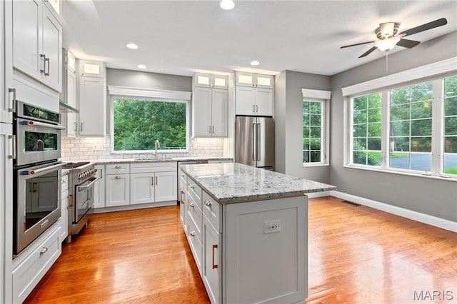 809 Star Ridge Ct, Defiance, MO 63341 - kitchen featuring appliances with stainless steel finishes, a center island, decorative backsplash, a ceiling fan, and recessed lighting