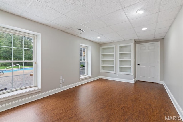 809 Star Ridge Ct, Defiance, MO 63341 - empty room featuring dark wood-type flooring, built in shelves, a paneled ceiling, and recessed lighting