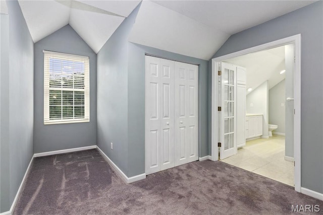 809 Star Ridge Ct, Defiance, MO 63341 - unfurnished bedroom featuring lofted ceiling, carpet, a closet, and tile patterned flooring