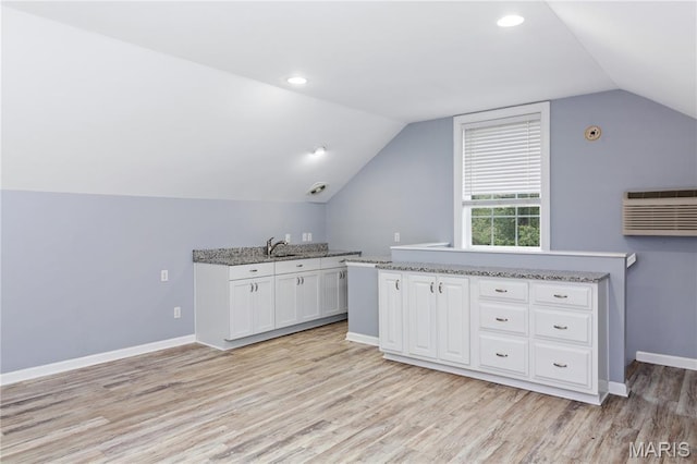 809 Star Ridge Ct, Defiance, MO 63341 - kitchen with white cabinetry, light wood-style flooring, lofted ceiling, an AC wall unit, and light stone countertops