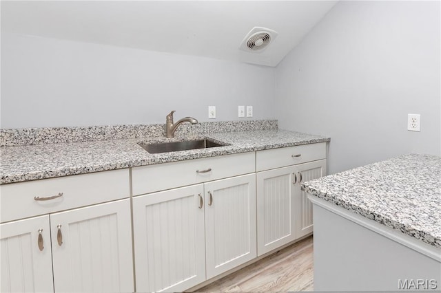 809 Star Ridge Ct, Defiance, MO 63341 - kitchen with light wood finished floors, light stone countertops, and white cabinetry