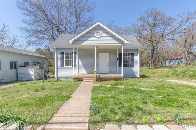 bungalow featuring a front yard, covered porch, and a shingled roof