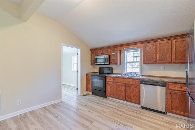 kitchen with stainless steel appliances, a sink, brown cabinets, lofted ceiling, and light wood-type flooring