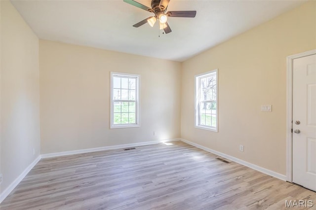 empty room with healthy amount of natural light, light wood finished floors, ceiling fan, and baseboards